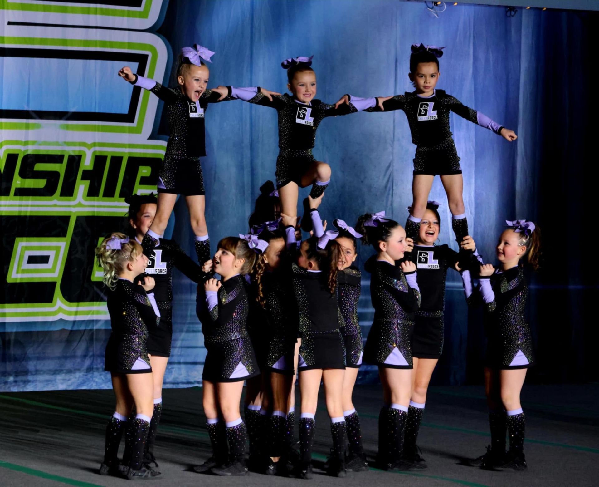 A group of cheerleaders are performing a stunt in front of a sign that says smash
