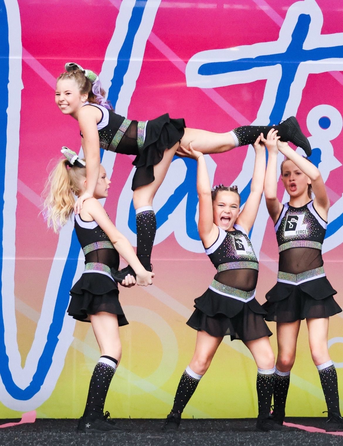 A cheerleader is being lifted in the air by two other cheerleaders