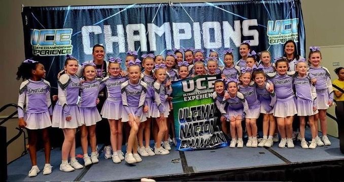 A group of cheerleaders are posing for a picture on a stage.