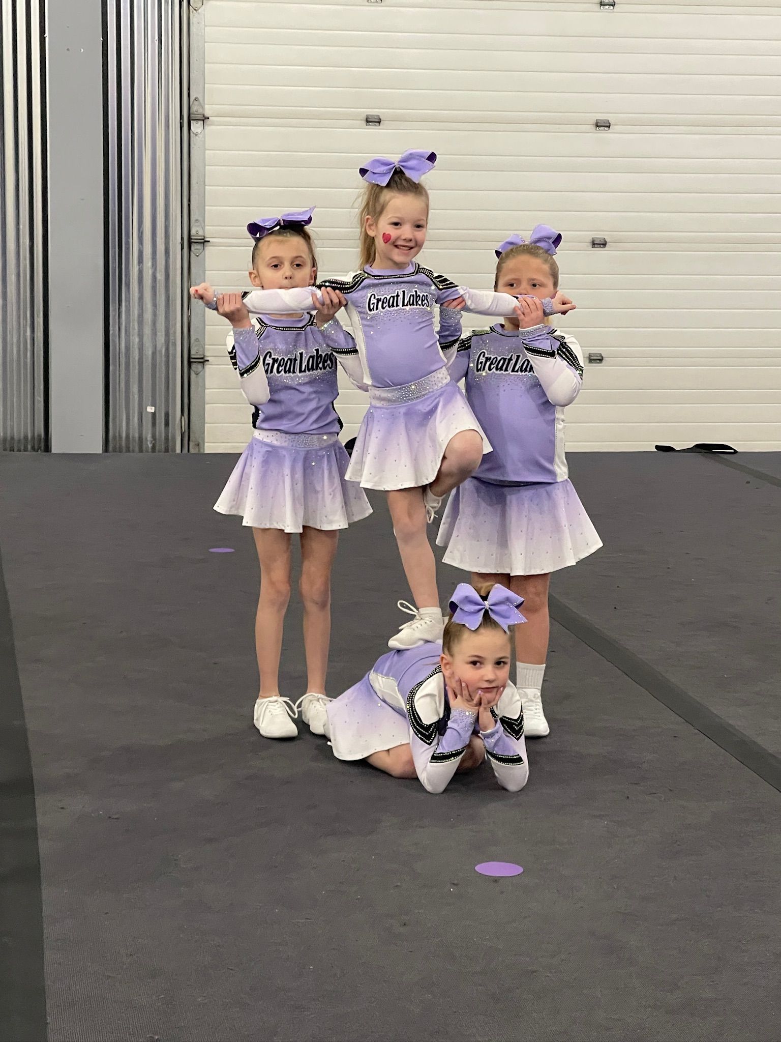 A group of young cheerleaders are posing for a picture on a gym floor.