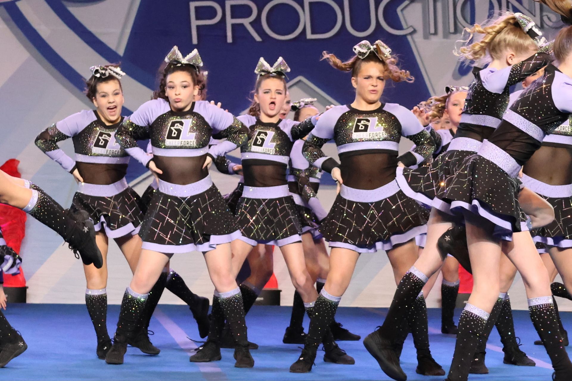 A group of cheerleaders are performing in front of a sign that says production
