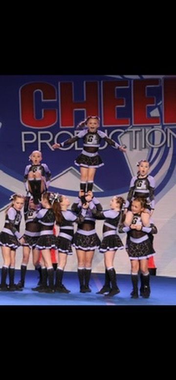 A group of cheerleaders are performing in front of a sign that says cheer production