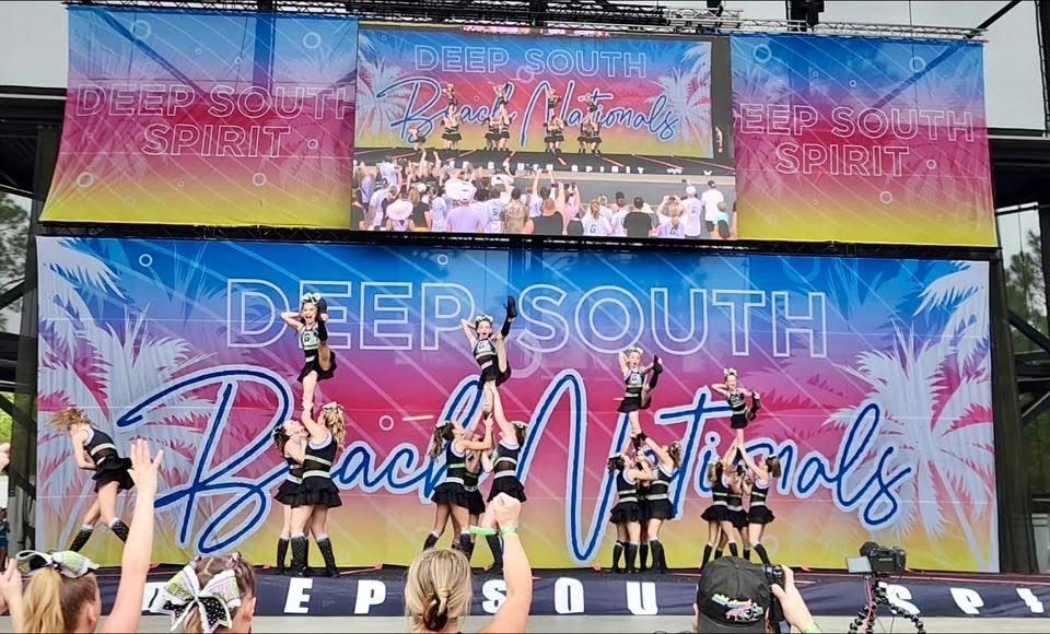 A group of cheerleaders are performing on a stage at a beach festival.