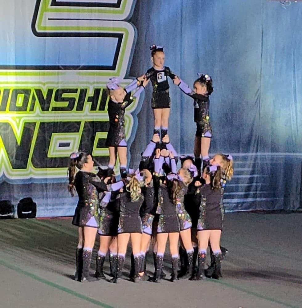 A group of cheerleaders are performing in front of a sign that says championships