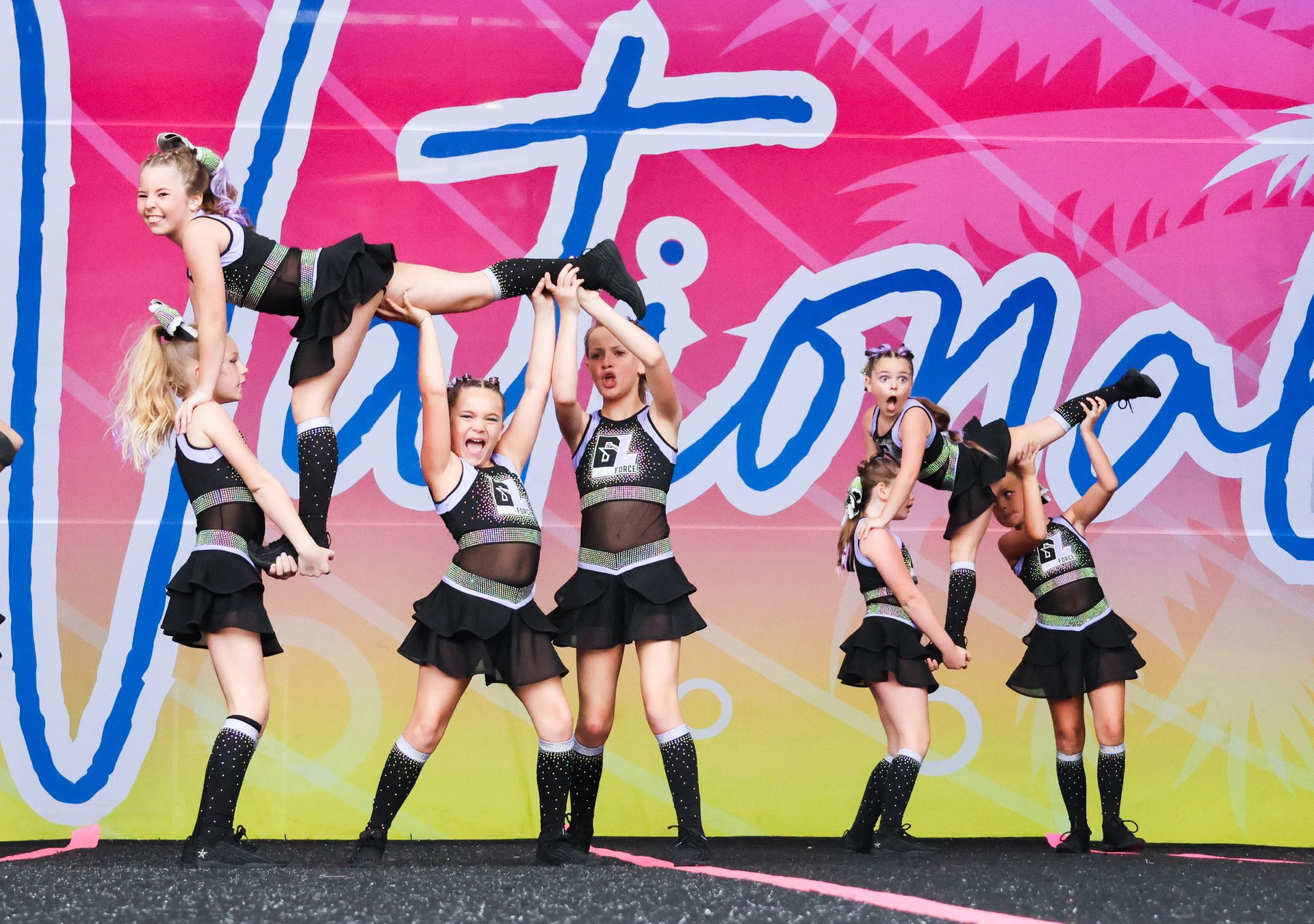 A group of cheerleaders are performing in front of a sign that says national