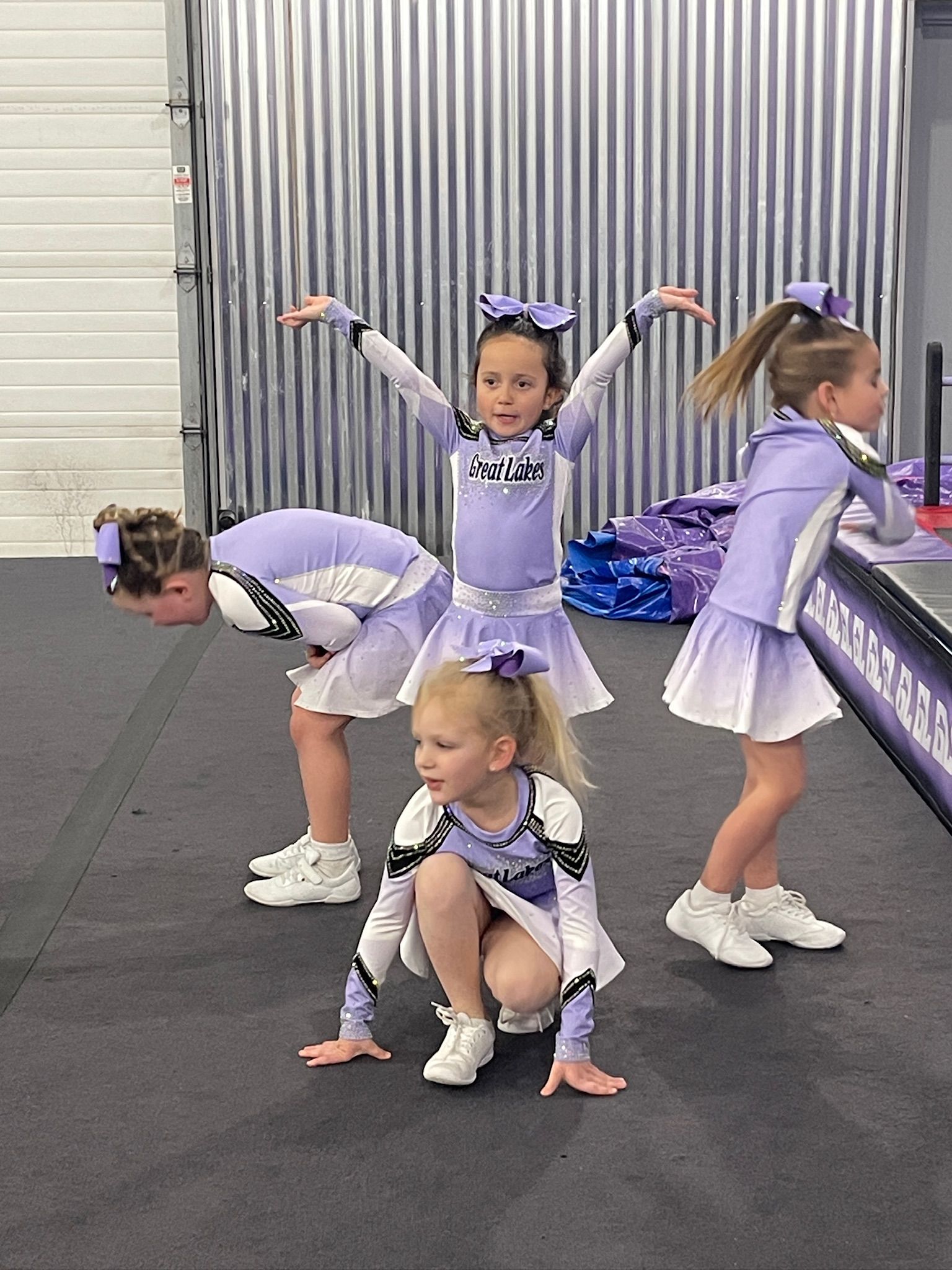 4 little girls cheering together in purple outfits
