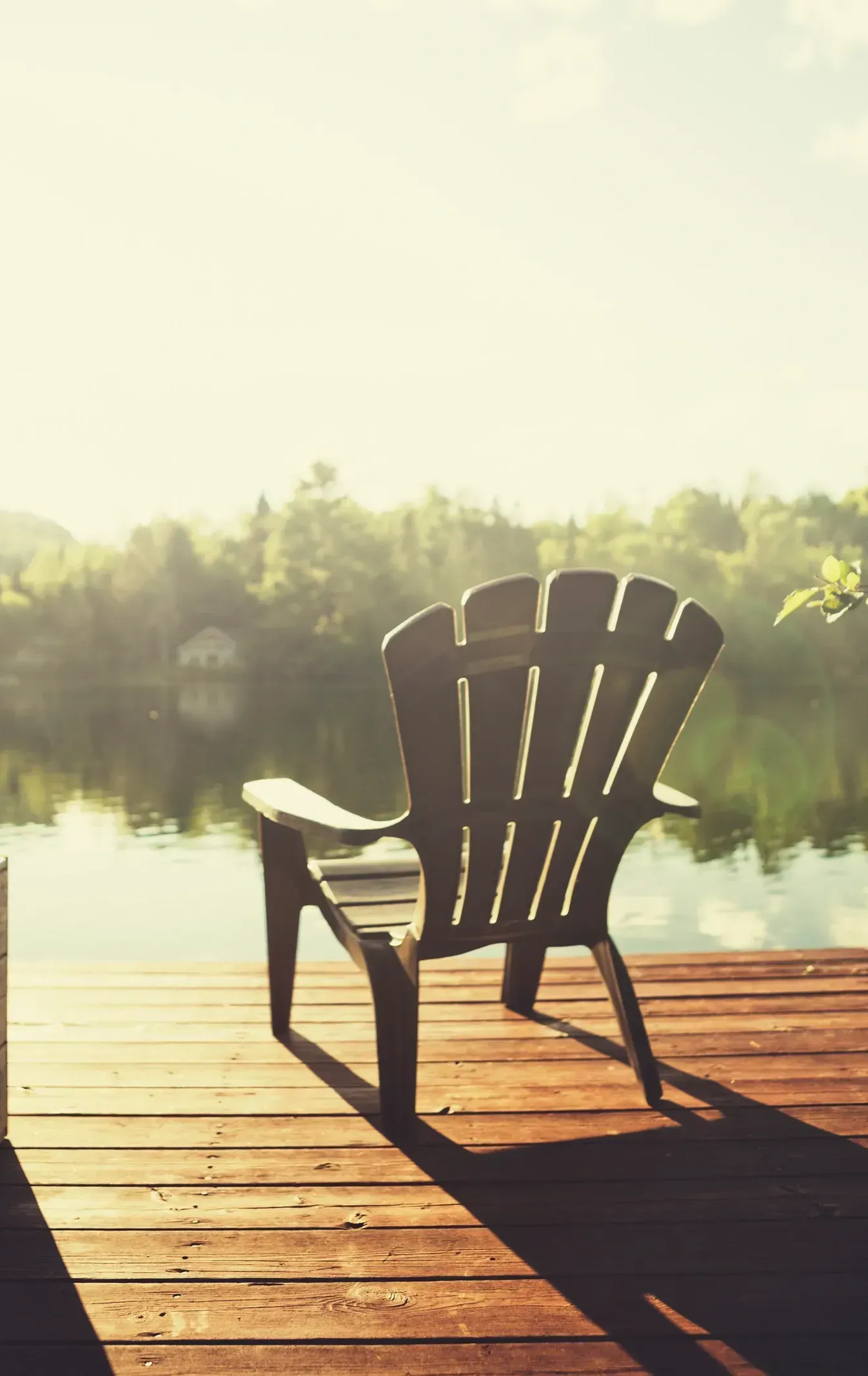 Wooden Adirondack chair on a dock overlooking a calm lake, sunny day. — AT My Place Counselling and Psychotherapy in North Sydney, NSW