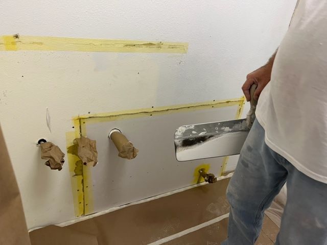 A kitchen is being remodeled with wooden cabinets and a microwave.