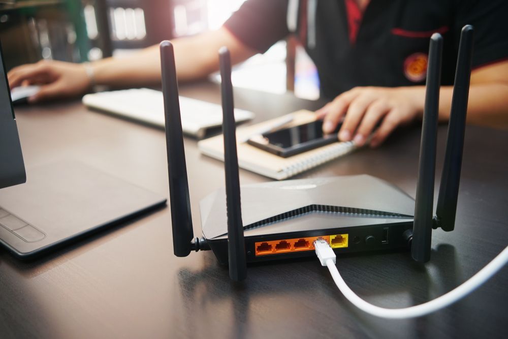 Wi-fi Router On Desk With Person Using Devices In Background — Shane Kelly Communications in Northern Rivers, NSW