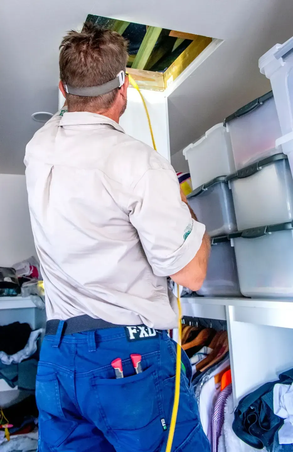 Man In Work Clothes Inspecting An Attic Access. White Closet — Shane Kelly Communications in Northern Rivers, NSW