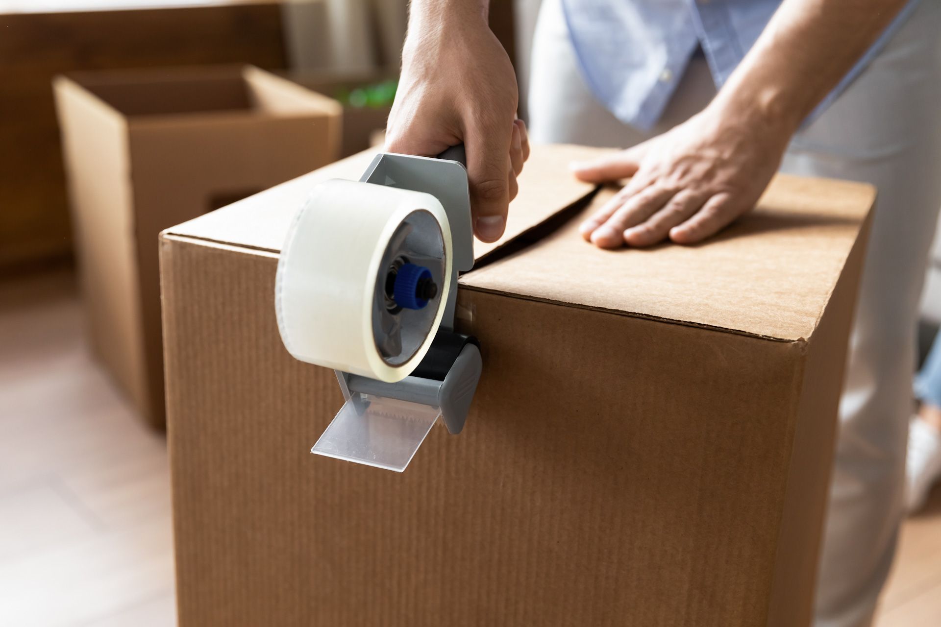 A person is taping a cardboard box with tape.