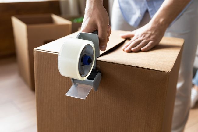 A person is taping a cardboard box with tape.