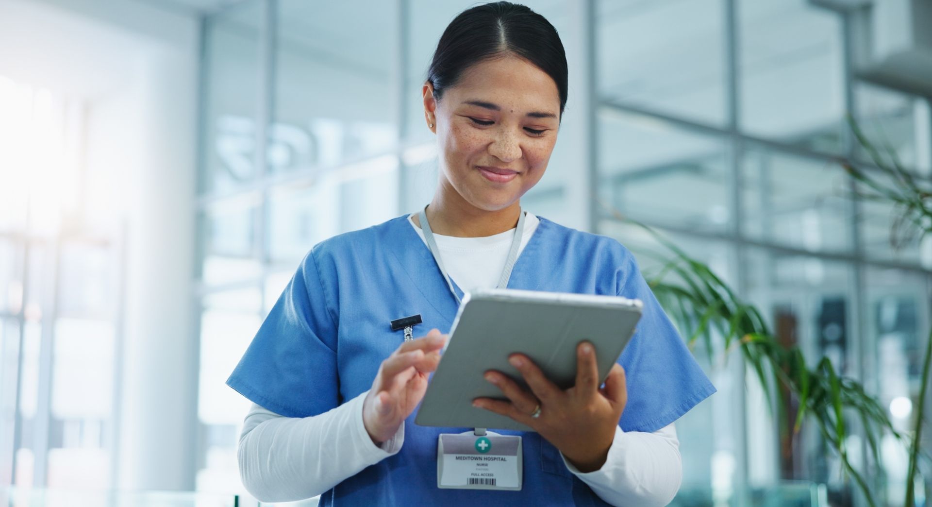 A nurse wearing headphones is sitting in front of a laptop computer.