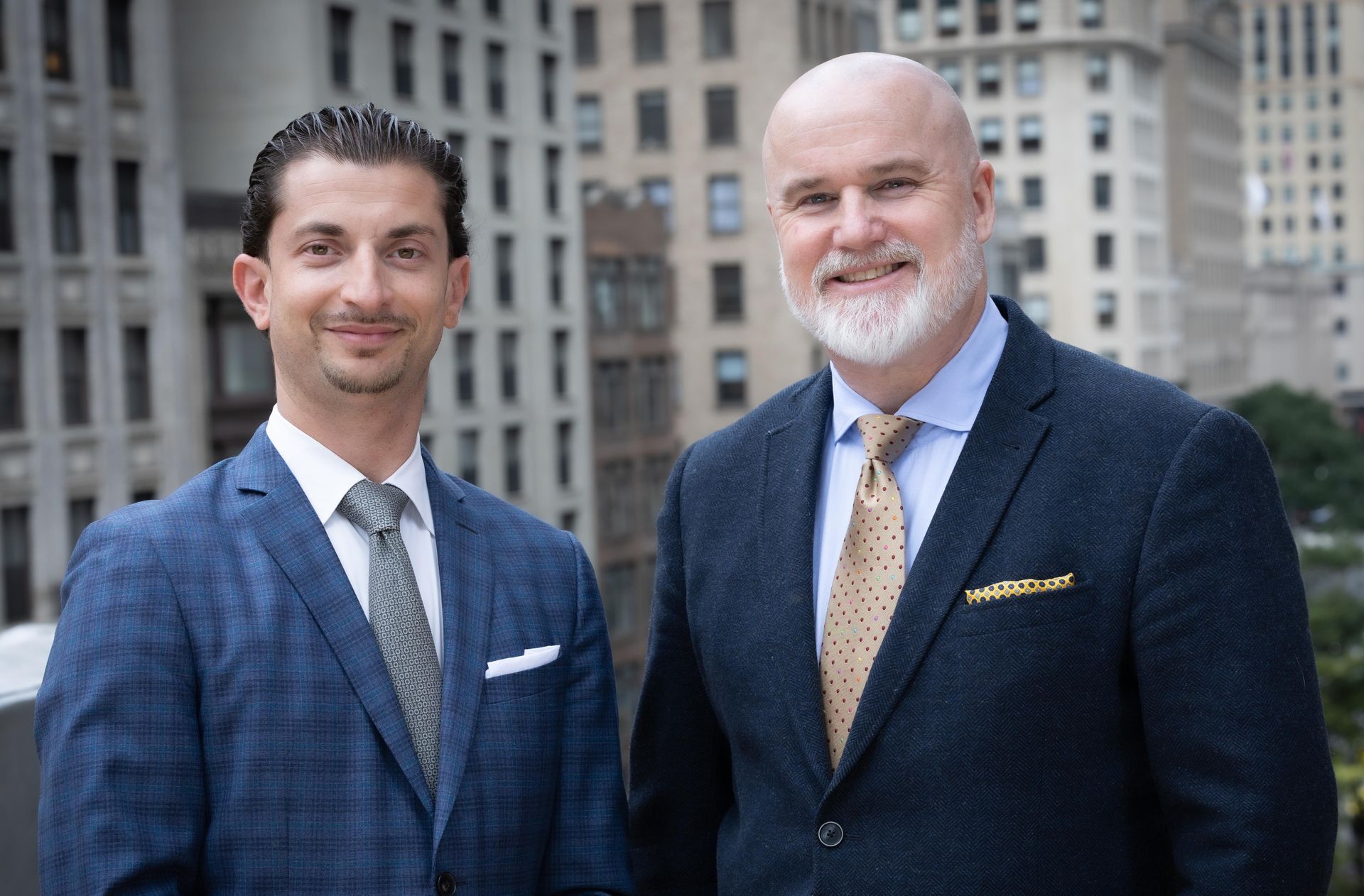 Two men in suits and ties are standing next to each other in front of a city skyline.