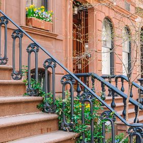 A set of stairs leading up to a building with a wrought iron railing.