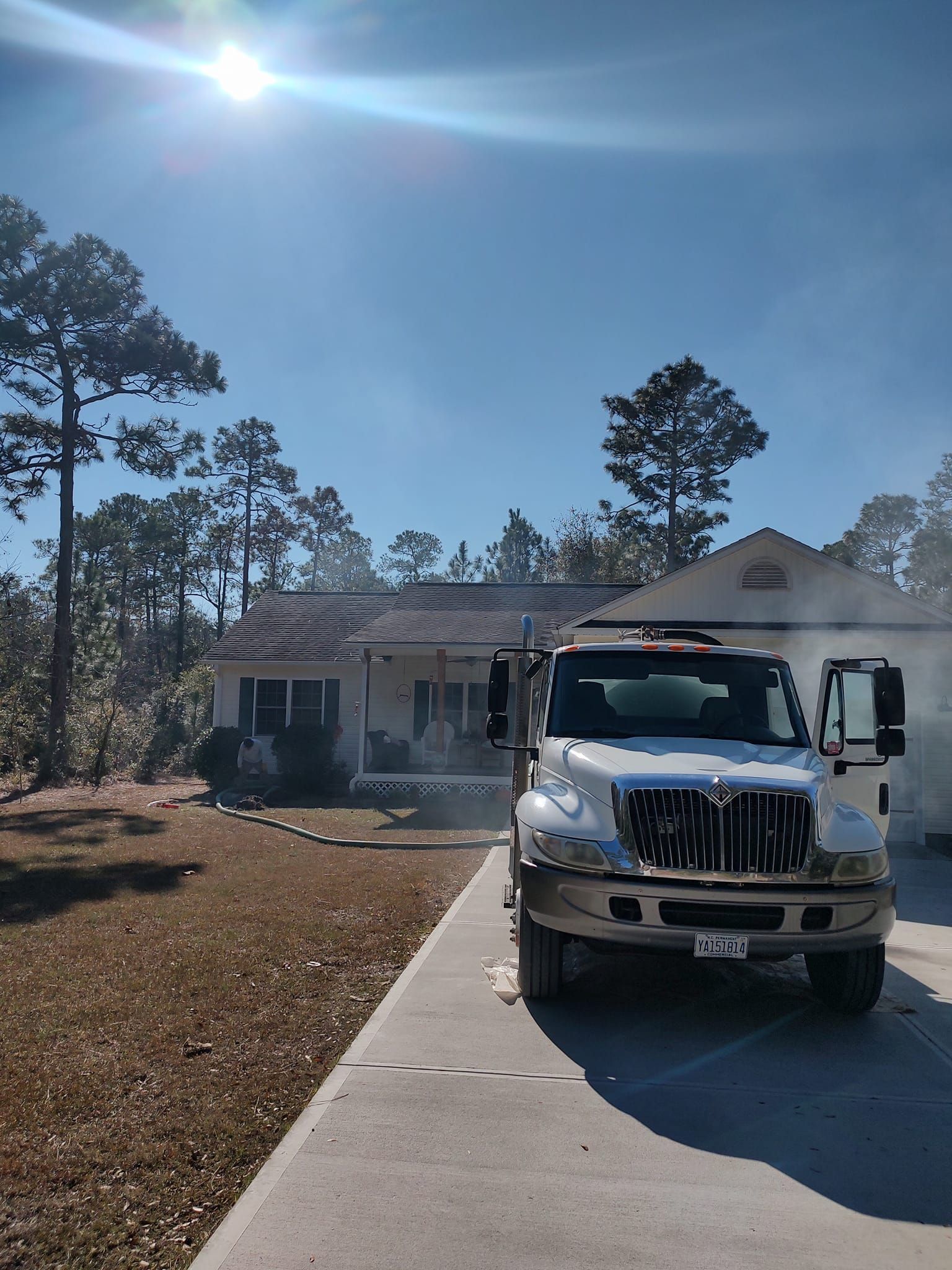 A white truck is parked in front of a house on a sunny day.