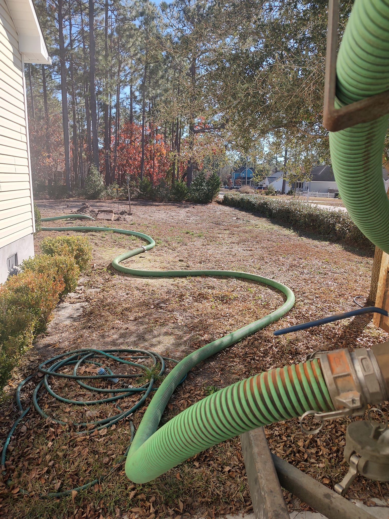 A green hose is being used to pump sewage into a house.