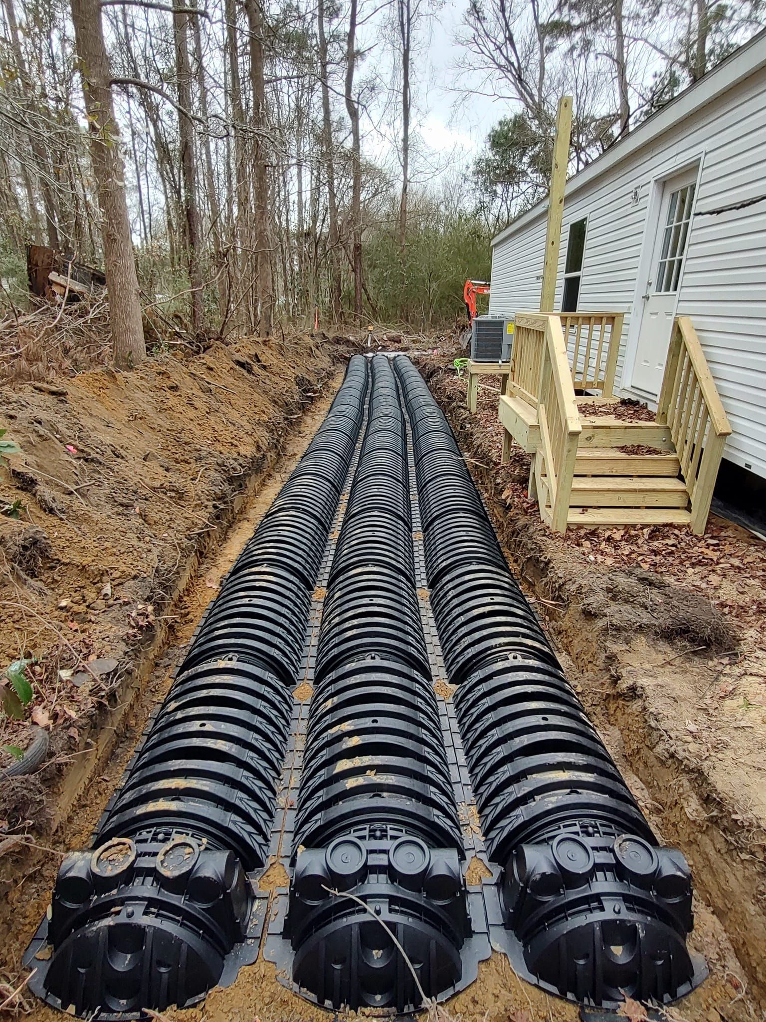 A septic system is being installed in the backyard of a mobile home.