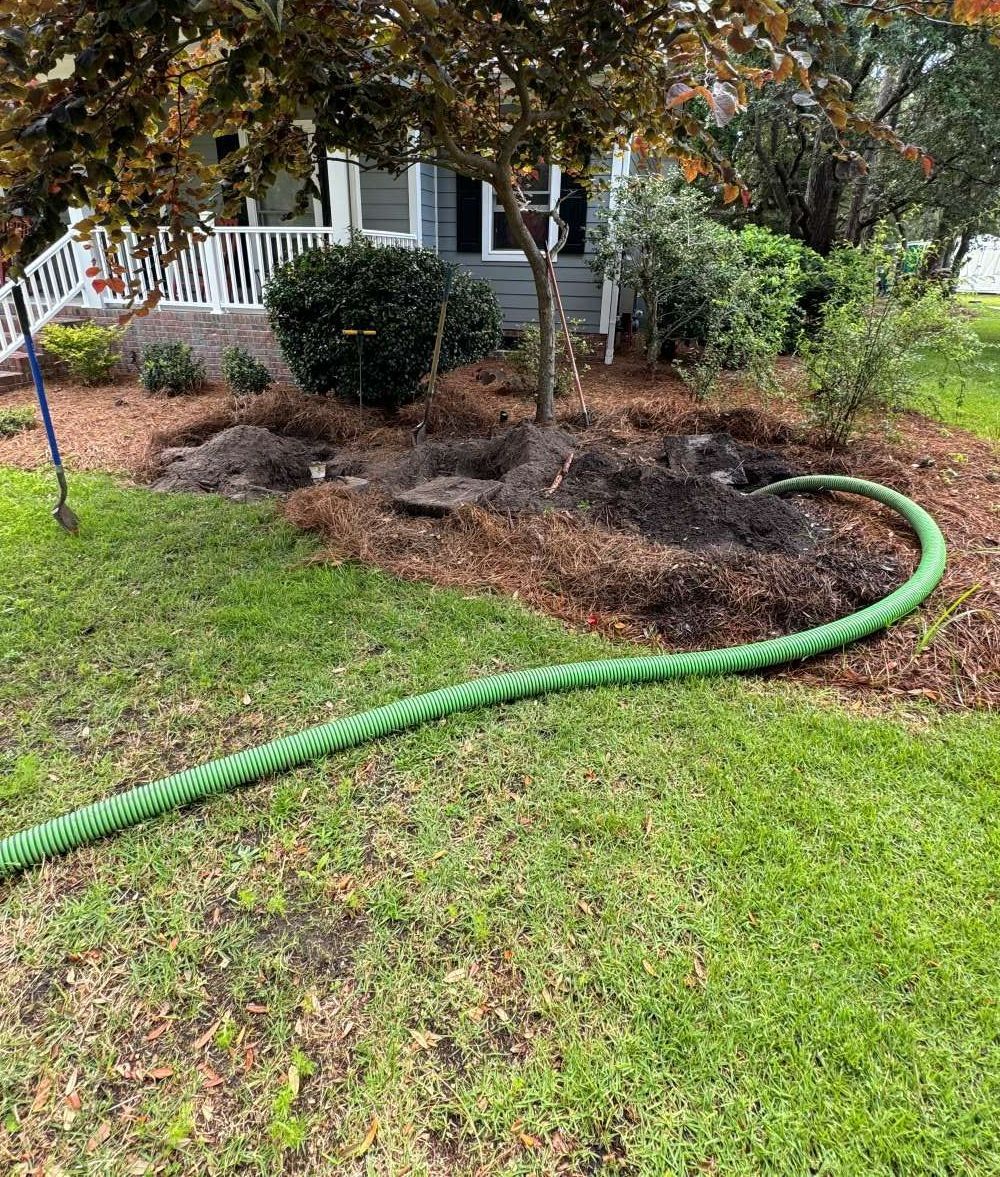 A green hose is sitting in the grass in front of a house.