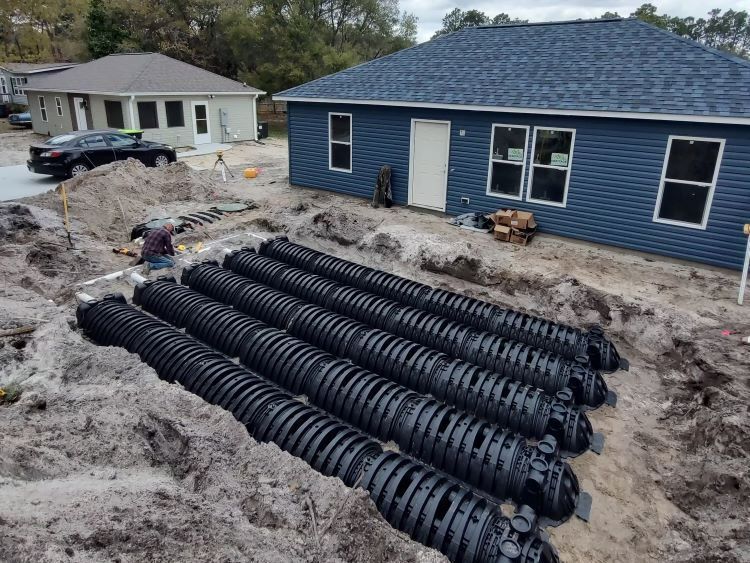 A man is working on a septic system in front of a house.