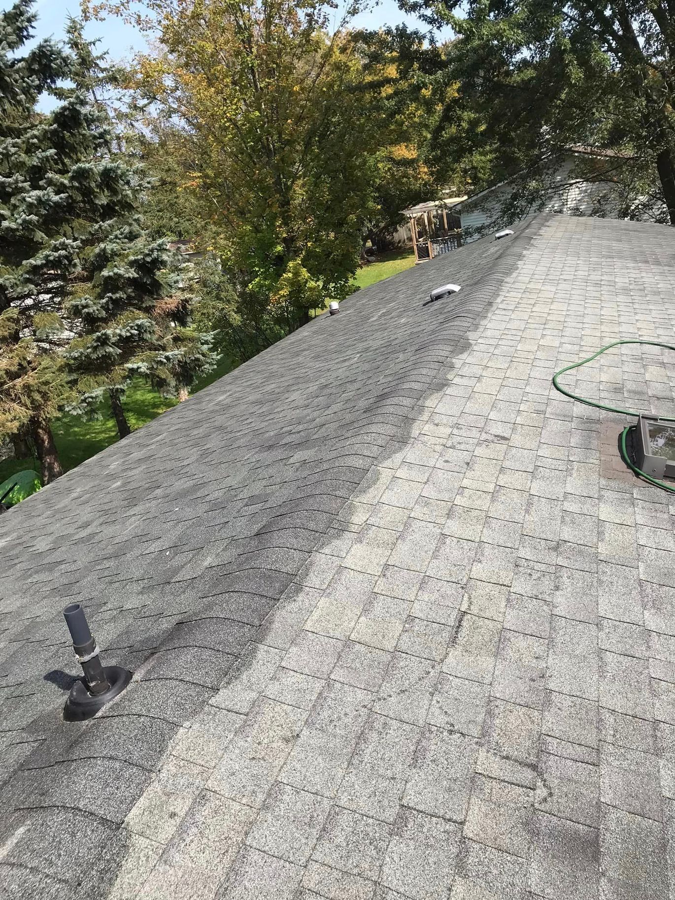 A roof with a lot of shingles on it and trees in the background.