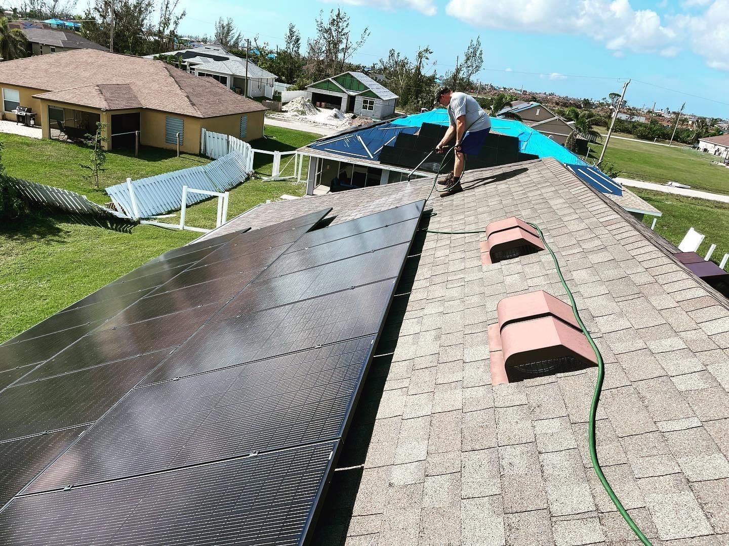 A man is working on the roof of a house with solar panels.