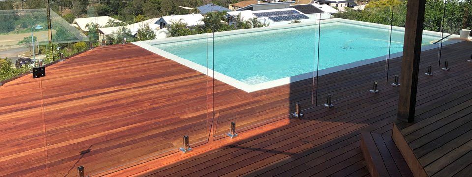 pool with wood deck and glass fence
