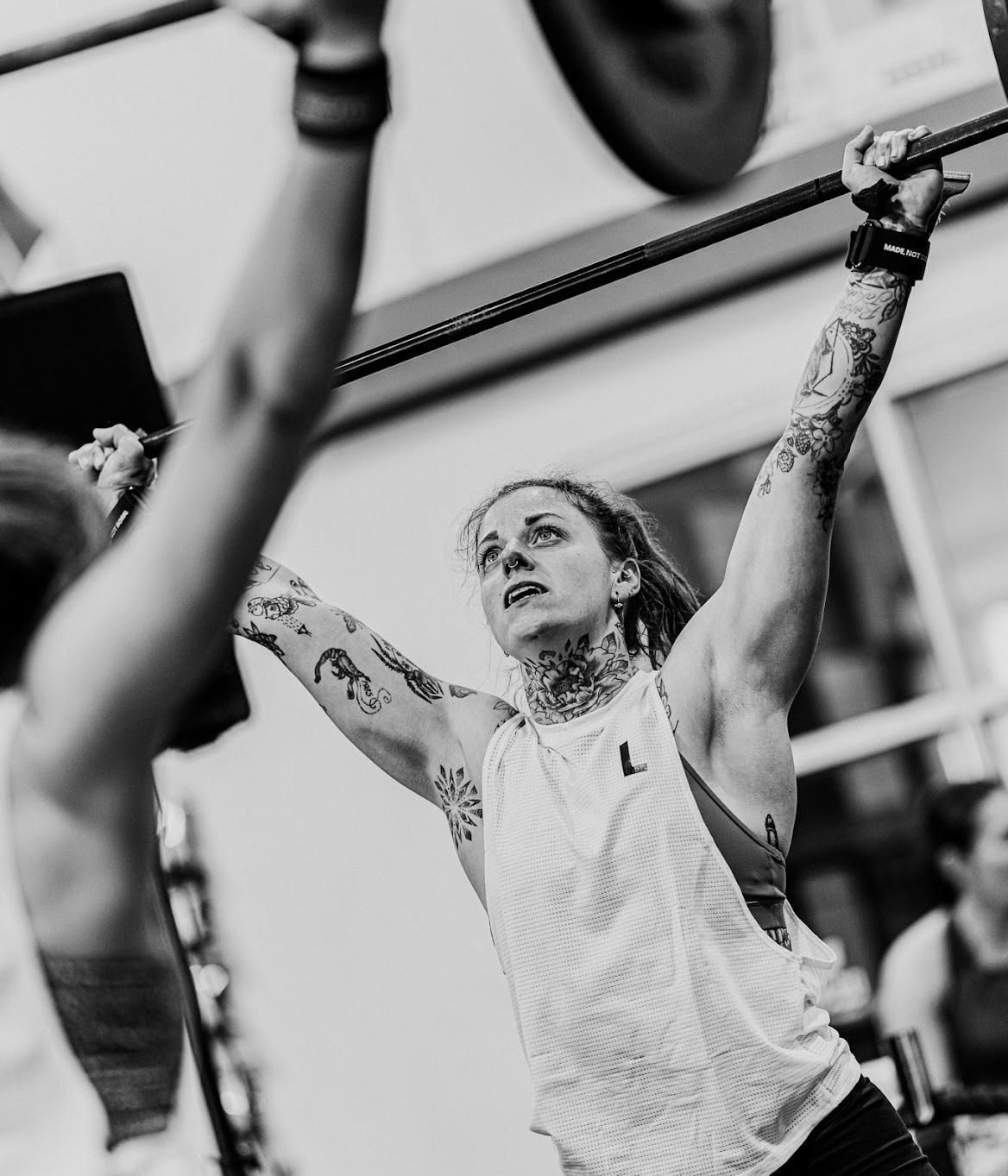 A person stands with arms crossed in front of a sign that reads 