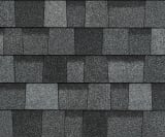 Close-up view of asphalt roofing shingles in varying shades of gray, creating a textured, layered pattern.