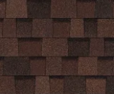 A close-up of overlapping asphalt roofing shingles in varying shades of dark brown and black.