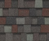 Close-up of architectural asphalt roof shingles with a varied pattern of dark gray, charcoal, and reddish-brown tones.