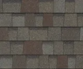 A repeating texture of layered, charcoal and brown rectangular asphalt roofing shingles.