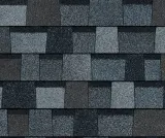 A close-up of charcoal and slate-gray architectural roofing shingles with a textured, layered appearance.