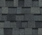 Close-up of overlapping charcoal gray architectural roof shingles with a varied, textured pattern.