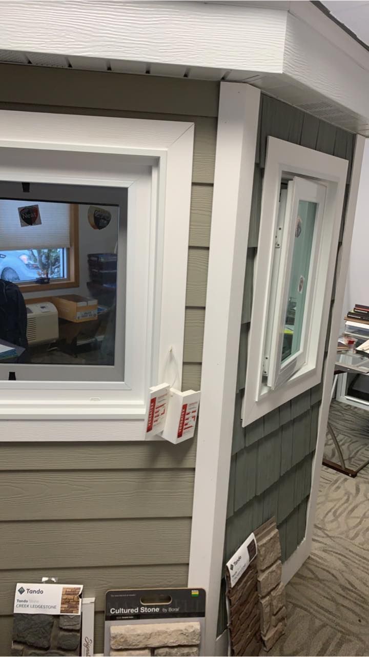 A corner display showing beige horizontal lap siding and grey shingle siding, each featuring a white-framed window.