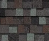 A close-up view of overlapping architectural asphalt roof shingles in blended shades of charcoal, slate gray, and brown.