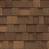 A repeating pattern of rectangular brown asphalt roof shingles with variegated tones.