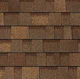 A close-up texture of brown architectural roofing shingles with overlapping, rectangular panels in varied earth tones.