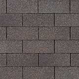 A repeating pattern of dark gray, rectangular asphalt shingles arranged in a staggered, overlapping brickwork layout.