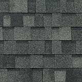 A pattern of dark gray and charcoal architectural asphalt shingles with a textured, multi-toned appearance.
