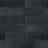 A close-up, top-down view of black, rectangular architectural roof shingles laid in an overlapping, offset pattern.