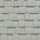 A repeating pattern of light gray, rectangular asphalt roof shingles with a textured, granulated surface.
