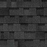 A close-up of dark grey, layered architectural asphalt roof shingles with a textured, overlapping pattern.