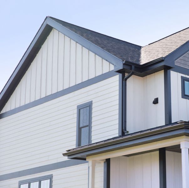 A side view of a modern two-story house exterior featuring white horizontal and vertical siding with dark gray trim.