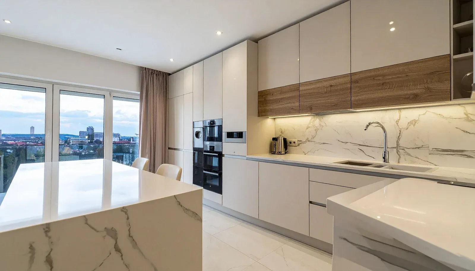 Exterior view of a tan brick house corner with a brown downspout and a stone-walled garden bed next to a lawn.
