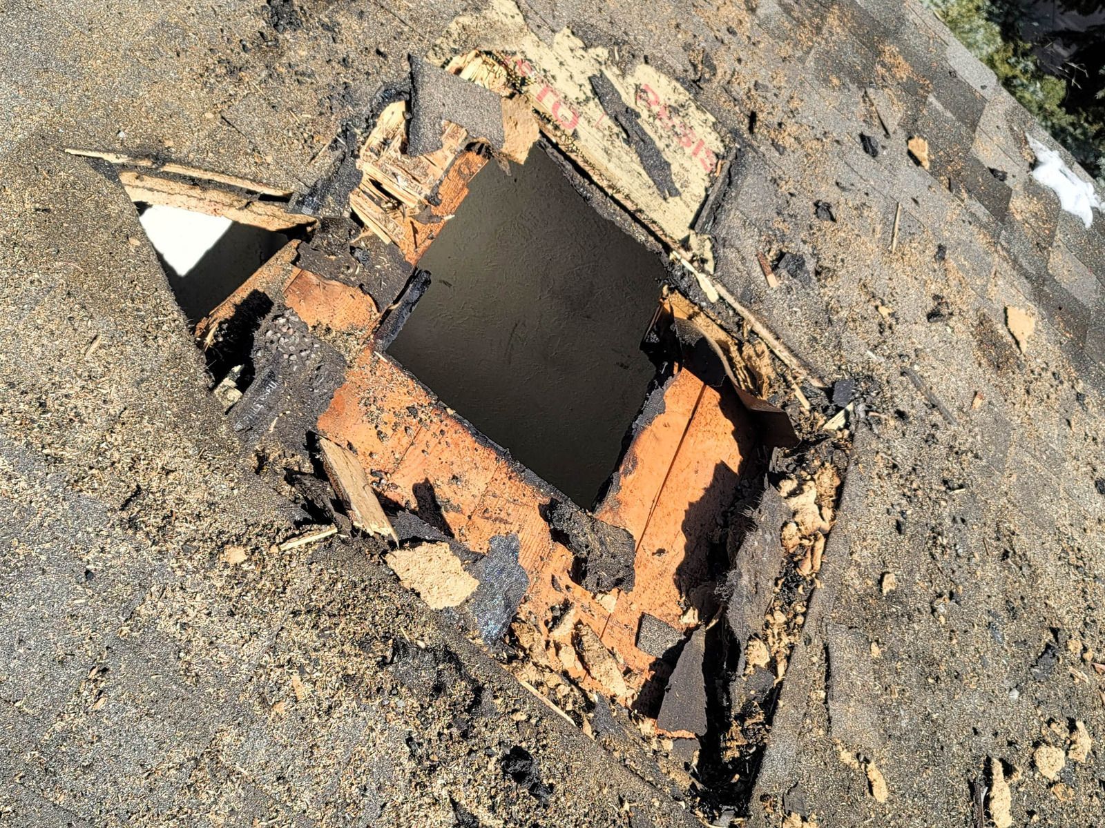 Side view of a light-colored house with dark brown trim, a red roof, a white gutter, and a wooden privacy fence.