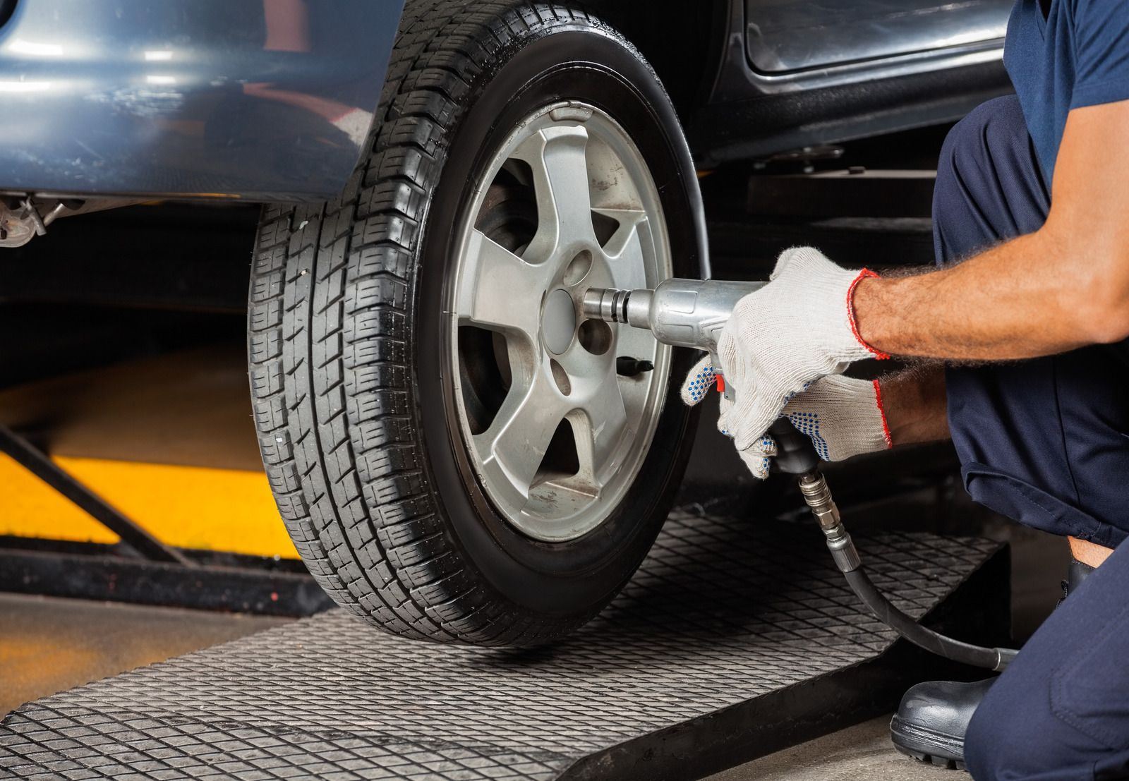 A man is changing a tire on a car in a garage.