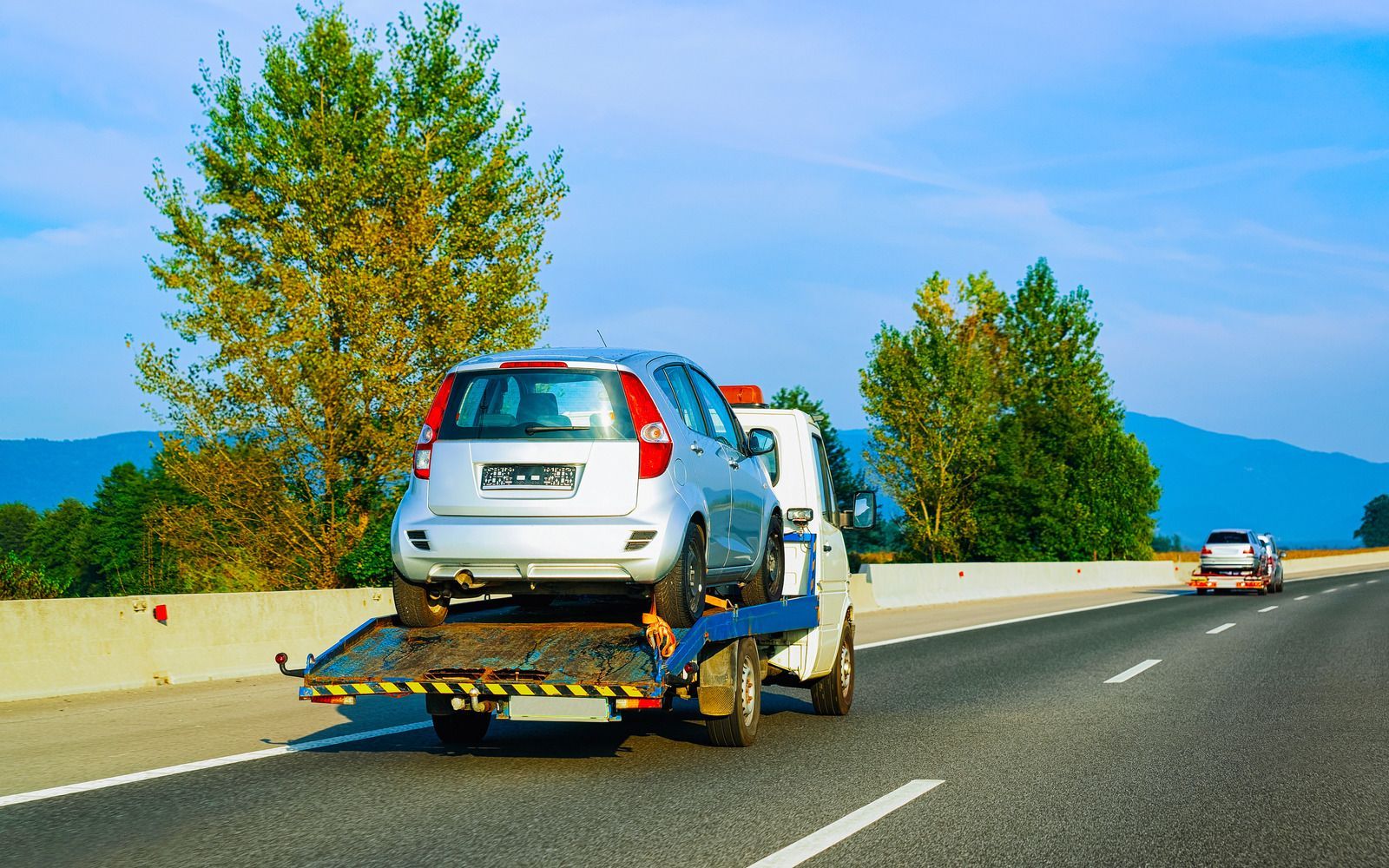 A tow truck is towing a car on the side of the road.