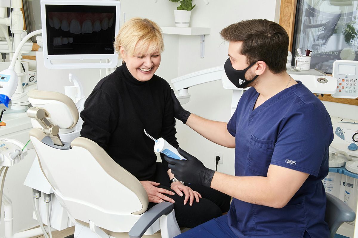 Dentist showing a device to a smiling patient in a dental office.