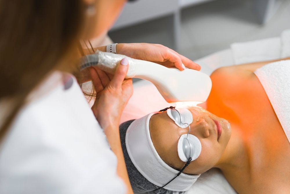 A woman is getting a laser treatment on her face.